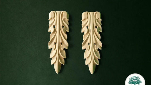 two ornate wooden leaf-shaped ornaments, each with a unique design, set against a dark green background.