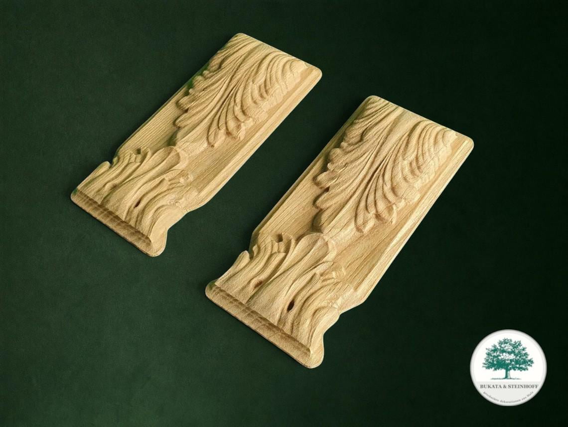 two intricately carved wooden pieces with detailed leaf-like designs, set against a dark green background.