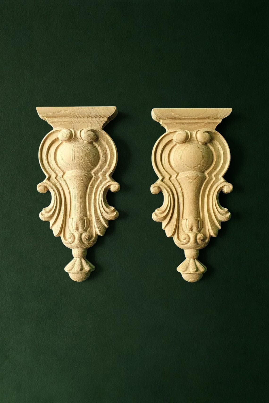 two ornate wooden wall hangings with intricate carvings, displayed against a dark green background.