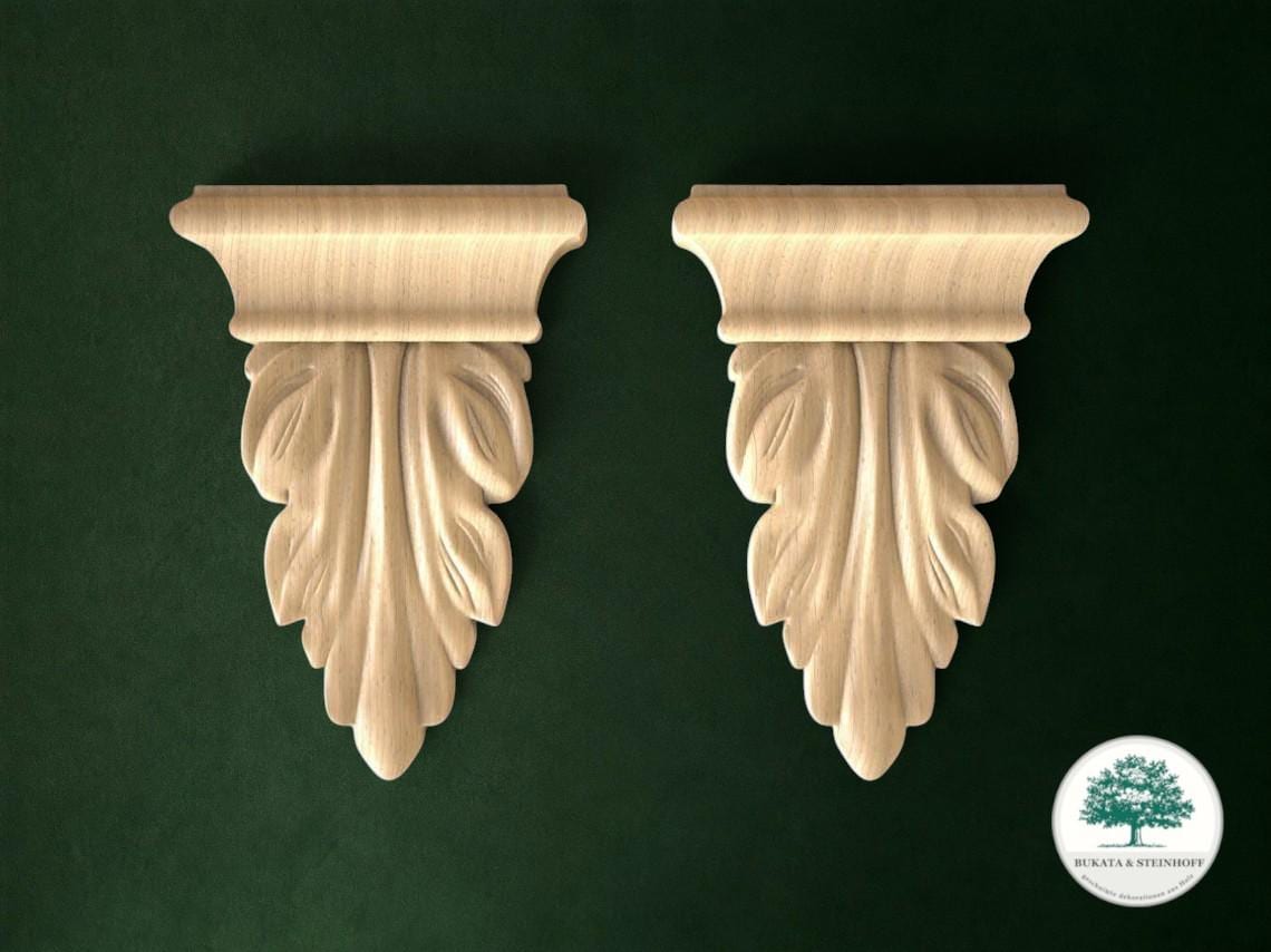 two ornate wooden wall sconces with leaf-like designs on a dark green background.
