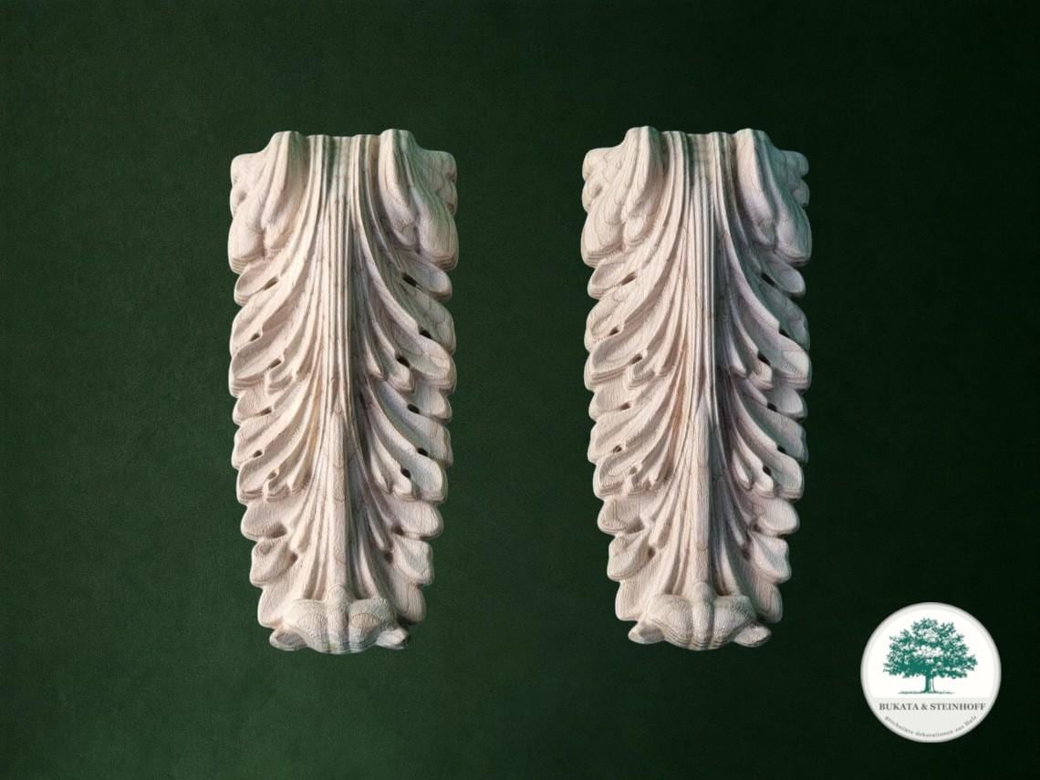 two ornate, carved stone sculptures with intricate, flowing designs, set against a dark green background.