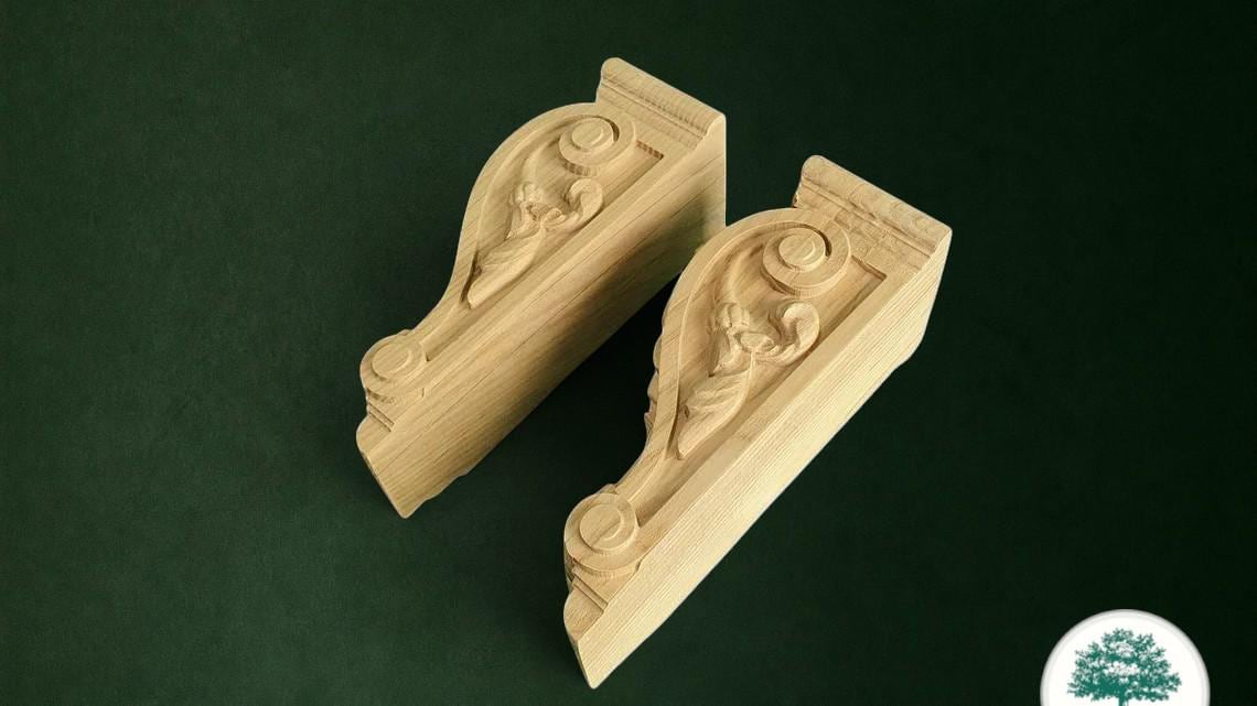 two intricately carved wooden brackets against a dark green background.